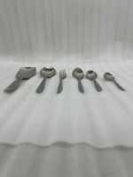 A high-angle view of a complete 53-piece stainless steel cutlery set arranged neatly on a wooden table, as displayed in 7.jpg