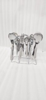 A fork and spoon from the 37-piece stainless steel cutlery set elegantly placed on a linen napkin next to a freshly served pasta dish.
