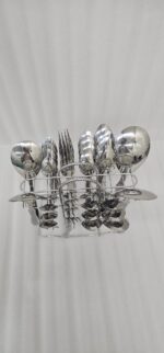 A fork and spoon from the 37-piece stainless steel cutlery set elegantly placed on a linen napkin next to a freshly served pasta dish.
