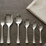 An elegant assortment of stainless steel flatware, including various spoons, forks, and knives arranged on a wooden table as featured in 6.jpg, representing a complete 53-piece dining set.