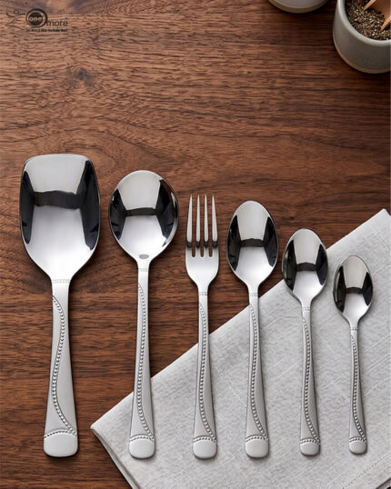 Overhead view of a 37-piece stainless steel cutlery set, including table spoons, forks, knives, and serving utensils arranged on a wooden table, as depicted in 7.jpg.