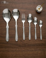High-quality stainless steel cutlery set featuring table spoons, tea spoons, forks, and serving utensils arranged on a dark wooden background, as displayed in 7.jpg.