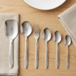 A high-angle view of a complete 53-piece stainless steel cutlery set arranged neatly on a wooden table, as displayed in 7.jpg