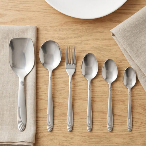 A high-angle view of a complete 53-piece stainless steel cutlery set arranged neatly on a wooden table, as displayed in 7.jpg