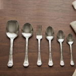 A complete 53-piece stainless steel dining cutlery set featuring spoons, forks, knives, and a serving stand displayed elegantly on a wooden background, as featured in 8.jpg.