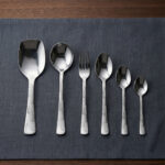 A high-quality 53-piece stainless steel cutlery set featuring elegant patterned handles, displayed on a grey fabric surface as shown in 9.jpg.