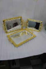 An elegant rectangular stainless steel serving tray with a highly reflective mirror finish and intricate center engravings, featuring a luxurious ornate gold border and decorative handles, displayed on a dark wooden table as shown in 1.jpg.