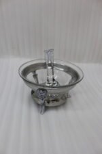 One More premium glass serving bowl set with an ornate silver-plated stand and two matching serving spoons placed on a dining table.