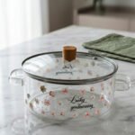 Alt Text: One More 2.5L square glass pot with floral prints, clear glass lid, and a wooden knob resting on a marble countertop.