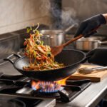 A 30cm granite-coated non-stick open wok being cleaned on a countertop, showcasing its durable surface.