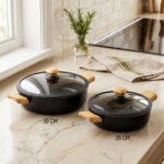 Two black, Made-in-Turkey granite non-stick casserole pots (26cm and 30cm) with wooden-look handles and rubber-rimmed lids sitting on a marble kitchen countertop.