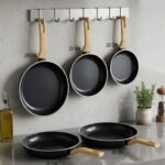 A collection of Turkish-made diamond-infused non-stick frying pans in various sizes ranging from 20cm to 30cm, displayed on a kitchen wall and countertop at OneMore.