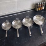 A set of four Made-in-Turkey stainless steel non-stick fry pans in sizes 20cm, 22cm, 24cm, and 26cm arranged on a kitchen counter.
