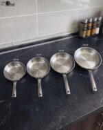 A set of four Made-in-Turkey stainless steel non-stick fry pans in sizes 20cm, 22cm, 24cm, and 26cm arranged on a kitchen counter.