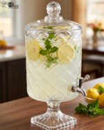 Elegant 4.5-liter diamond-cut glass beverage dispenser filled with infused lemon and cucumber water on an outdoor garden party table, featured in 2.jpg.