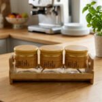 A set of three glass jars with bamboo lids and labels, neatly arranged on a wooden stand in a modern kitchen setting, as seen in 1.jpg.