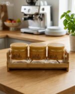 A set of three glass jars with bamboo lids and labels, neatly arranged on a wooden stand in a modern kitchen setting, as seen in 1.jpg.