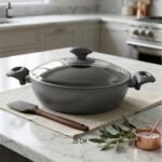 A premium 26cm non-stick granite pot made in Turkey, displayed on a kitchen counter with a matching glass lid and a spatula, available at OneMore.