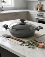 A premium 26cm non-stick granite pot made in Turkey, displayed on a kitchen counter with a matching glass lid and a spatula, available at OneMore.