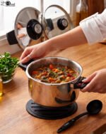 Falez 6L non-stick stainless steel 6-piece cooker set featuring a pot, lid, two spoons, and a heat-resistant table pad on a countertop.