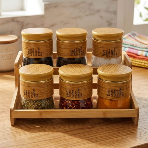 A set of six glass spice jars with wooden-look lids arranged on a matching tiered wooden stand, sitting on a kitchen countertop.