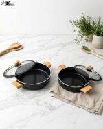 Two black, Made-in-Turkey granite non-stick casserole pots (26cm and 30cm) with wooden-look handles and rubber-rimmed lids sitting on a marble kitchen countertop.