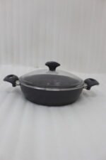 A premium 26cm non-stick granite pot made in Turkey, displayed on a kitchen counter with a matching glass lid and a spatula, available at OneMore.