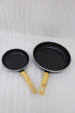 A collection of Turkish-made diamond-infused non-stick frying pans in various sizes ranging from 20cm to 30cm, displayed on a kitchen wall and countertop at OneMore.