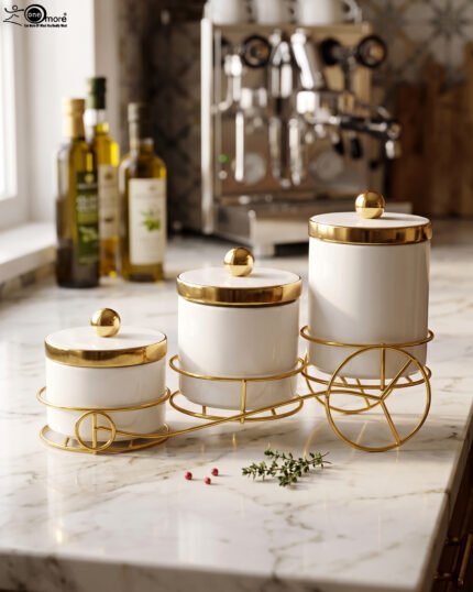 A set of three white ceramic jars with gold lids and spherical handles, elegantly arranged in a decorative gold metal cart stand against a white background.