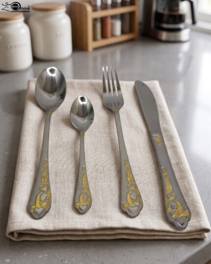 24 piece mirror polish stainless steel cutlery set with ornate gold heart handle detailing on a folded napkin