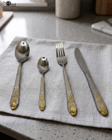 24-piece stainless steel cutlery set featuring gold "Love" engravings on handles, including rice spoon, sweet spoon, fork, and knife on a gray napkin.