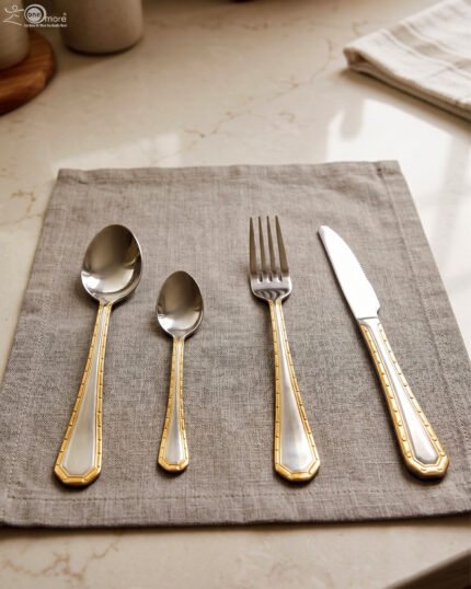 24-piece stainless steel cutlery set with gold-bordered handles including a rice spoon, sweet spoon, fork, and knife arranged on a grey placemat.