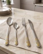 24 piece stainless steel cutlery set with gold rose embossed handles displayed on a cloth napkin