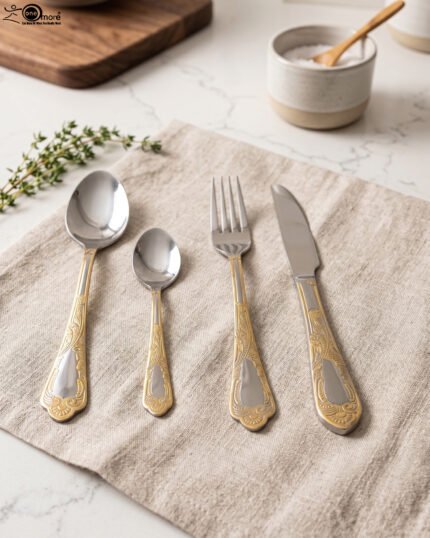 Luxury 24-piece stainless steel cutlery set with ornate gold embossed handles arranged on a linen napkin