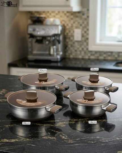 Four stainless steel double-handle woks with glass lids in 24cm, 26cm, 28cm, and 30cm sizes displayed on a dark kitchen countertop.