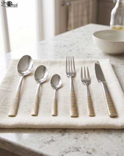36-piece stainless steel cutlery set with two-tone gold and silver textured handles displayed on a beige napkin.