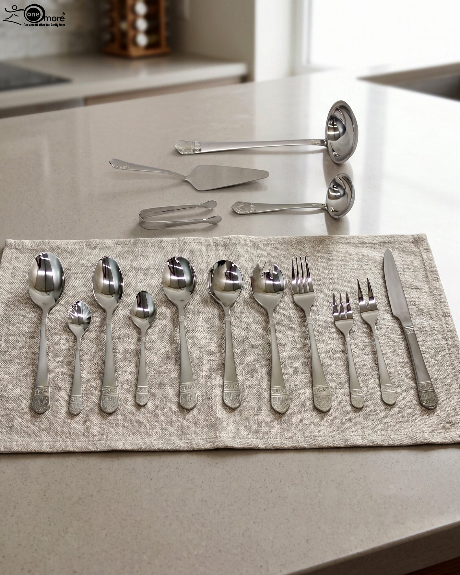 1 A Diverse Arrangement of Polished Silver-Toned Cutlery on a Textured Linen Mat, Featuring 12-Person Service and Loose Ladles, a Cake Server, and Tongs in the Background.