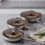Three sizes of premium non-stick titanium fry pans with matching glass lids and brown ergonomic handles displayed on a granite countertop.