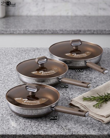 Three sizes of premium non-stick titanium fry pans with matching glass lids and brown ergonomic handles displayed on a granite countertop.