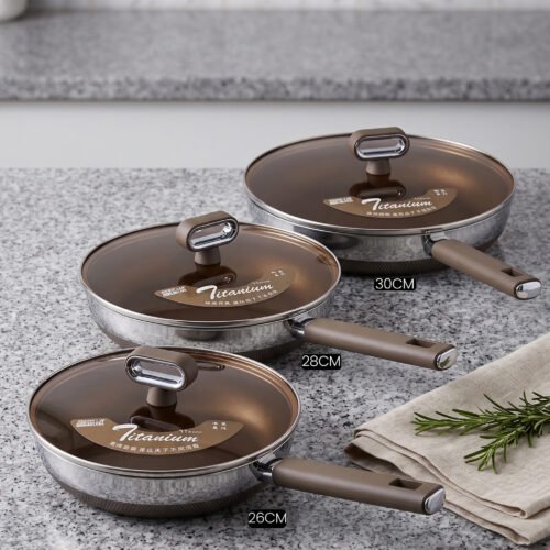 Three sizes of premium non-stick titanium fry pans with matching glass lids and brown ergonomic handles displayed on a granite countertop.