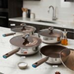 A collection of high-quality titanium stainless steel woks and frying pans in sizes 24cm, 26cm, 28cm, and 30cm with glass lids and ergonomic handles displayed on a kitchen counter.