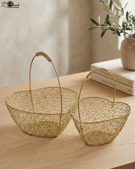 Two heart-shaped decorative gold wire mesh baskets with single handles set on a wooden table.