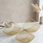 Set of three gold mesh wire decorative metal baskets displayed on a marble countertop with minimalist décor