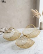 Set of three gold mesh wire decorative metal baskets displayed on a marble countertop with minimalist décor