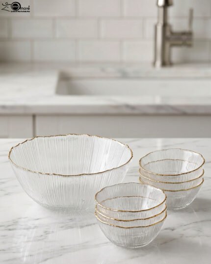 Two grey ribbed glass bowls with gold trim displayed together on a modern white marble countertop