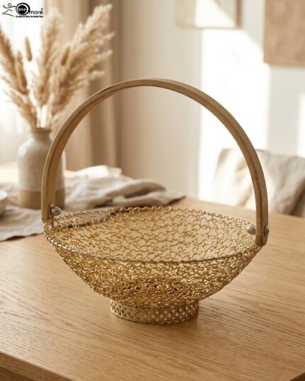 Gold decorative metal mesh basket with a curved wooden handle placed on a wooden table in a bright modern dining room