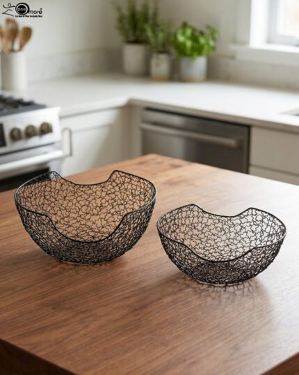 Set of two modern black wire mesh decorative baskets sitting on a wooden kitchen island countertop.