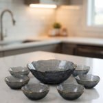 7-piece grey glass fruit set featuring one large serving bowl and six matching small bowls with gold rims, displayed on a kitchen countertop.