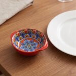 4-inch hand-painted decorative Marrakech ceramic piyali bowl with vibrant blue, yellow, and red pattern resting on a wooden table.