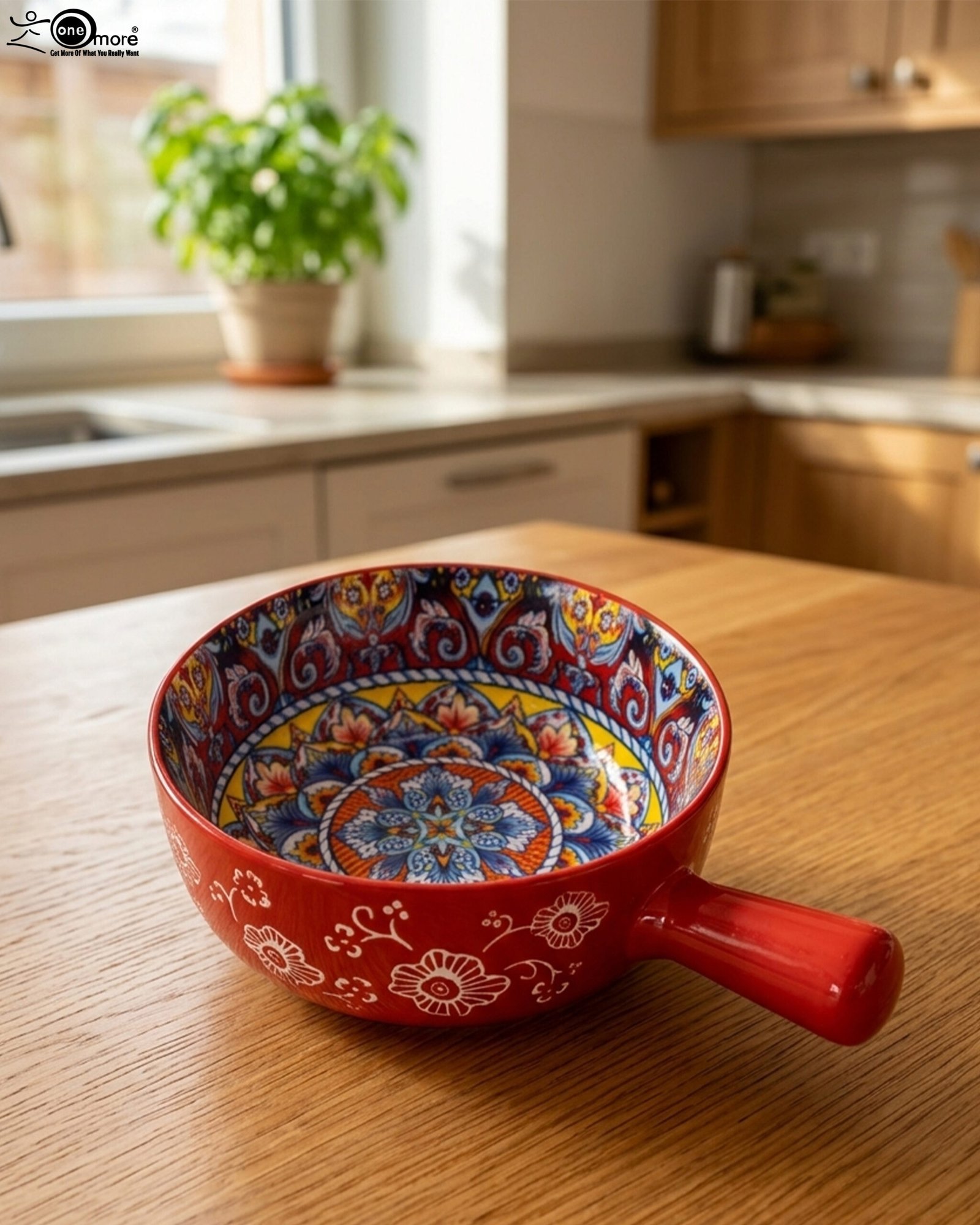 1 6-inch red ceramic Marrakech serving bowl with vibrant hand-painted geometric interior patterns and a single side handle sitting on a wooden kitchen island